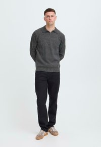Grauer Strickpullover mit Kragen, kombiniert mit schwarzen Hosen und grauen Sneakers mit weißen Streifen. Einfaches Design, leichte Textur.