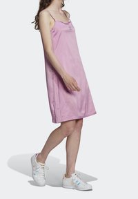 Różowa sukienka bez rękawów z okrągłym dekoltem i bocznymi szwami. Posiada wytłoczone logo na piersi oraz gładki, lekki materiał.
