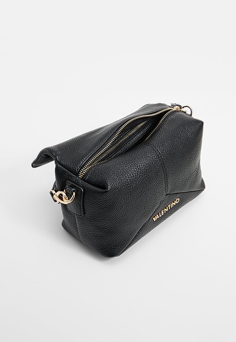 Trousse de maquillage en cuir noir avec une finition texturée, zip doré et détail de logo. Forme angulaire avec deux compartiments zippés.