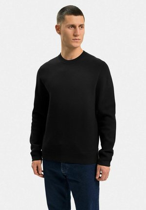 Sort crewneck sweater, lavet af et glat stof, med lange ærmer, en ribbet krave og en afslappet pasform. Bæres med blå jeans.