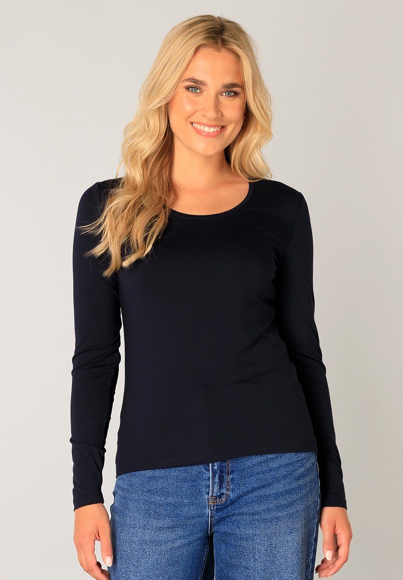 Langarm shirt in marineblauw met een ronde halslijn. Gemaakt van zachte, rekbare stof. De pasvorm is relaxed, gecombineerd met blauwe spijkerbroeken.