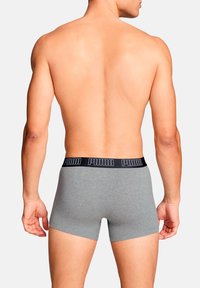 Graue Boxershorts aus weichem Stoff, mit einem schwarzen, gebrandeten Bund und einer engen Passform, von hinten betrachtet.