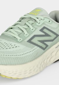 Αθλητικό παπούτσι New Balance ανοιχτού πράσινου χρώματος με επάνω μέρος από διχτυωτό υλικό, κορδόνια, μαλακή σόλα και σήμανση "evoz" στη γλώσσα και το πλάι.