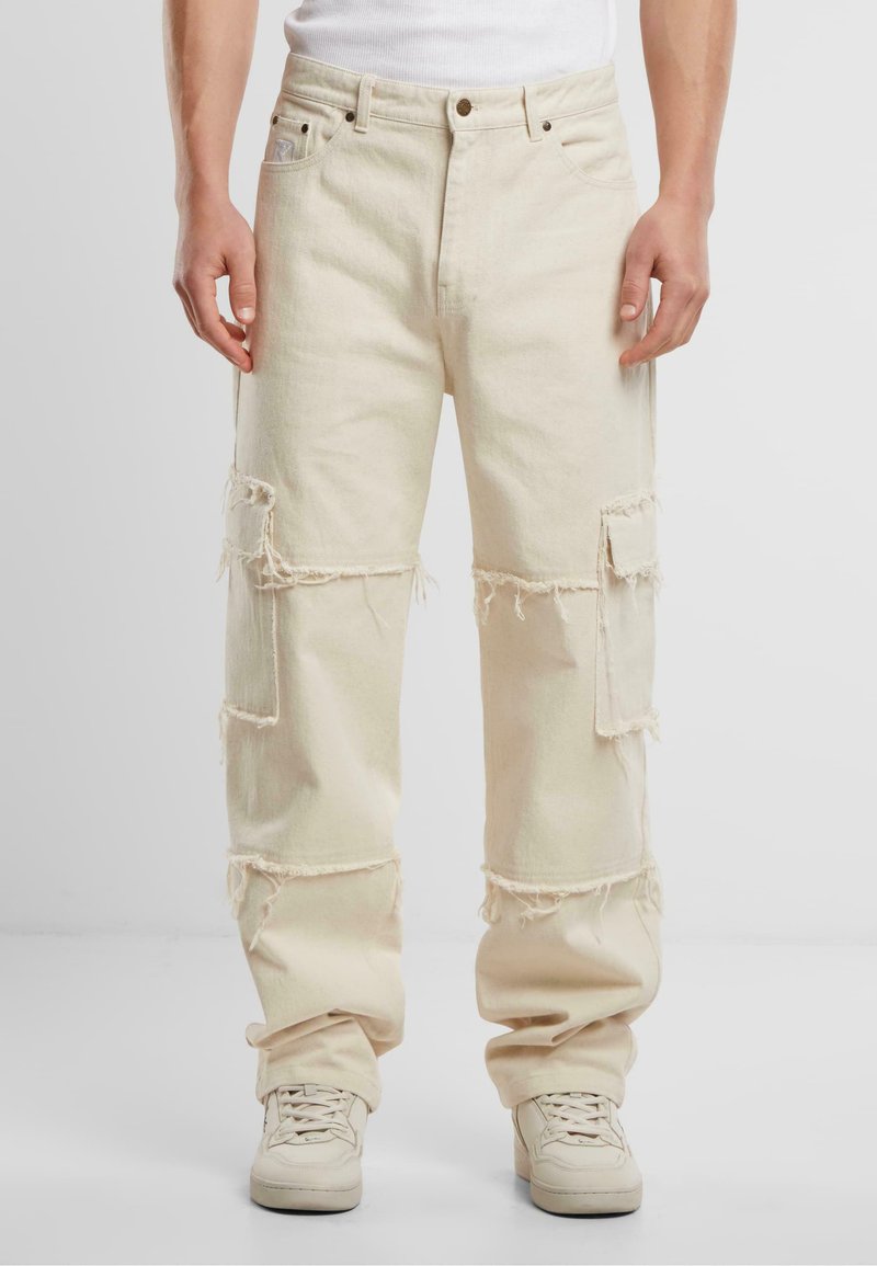 Pantaloni din denim bej, largi, cu margini descoase și multiple buzunare aplicate. Prezintă un închidere tradițională cu nasture și fermoar.