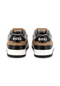 Brown leather sneakers with black accents, grey lining, white midsole, and black tread. "BOSS" logo on the heel. Low-top design.