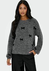 Grijze gebreide trui met een zachte textuur, voorzien van zwarte strikpatronen, ronde neklijn en losse lange mouwen.