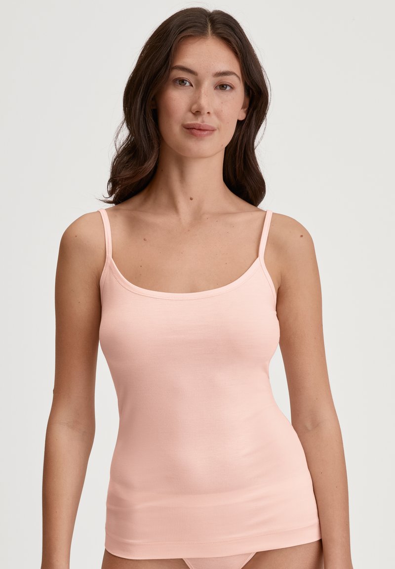 Light pink tank top with thin straps, made of a ribbed fabric. Features a straight neckline and a fitted silhouette.
