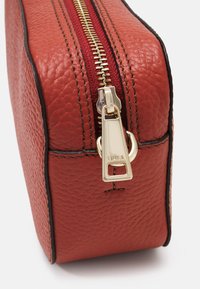 Borsa cosmetica rossa in pelle con una finitura testurizzata, caratterizzata da una zip dorata e cuciture a contrasto lungo i bordi.