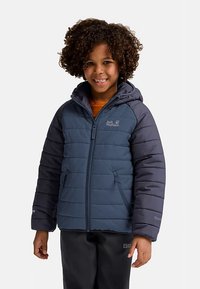 Tengerészkék színű szigetelt kabát kapucnival, steppelt mintával, cipzáras záródással és oldalzsebekkel. Mellrészen logó, sima textúra és testre szabott ujjak.