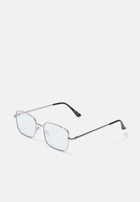 Ochelari cu ramă pătrată metalică, cu lentile clare și vârfuri negre contrastante pe brațe; design elegant și minimalist.