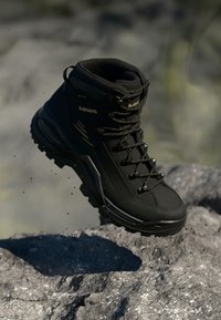 Schwarzer Wanderschuh mit gepolstertem Kragen, strukturiertem Obermaterial, verstärkter Zehenpartie und Gummisohle. Ausgestattet mit Schnürsystem und Logo-Detail.