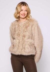 Beige Kunstpelzjacke mit rundem Kragen, frontalem Knopfverschluss und zwei aufgesetzten Taschen. Weicher Stoff und gerippter Saum am unteren Ende.