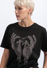 Zwarte katoenen T-shirt met een grafisch ontwerp van twee handen omwikkeld met garen, met gedetailleerde lijnen en een minimalistisch ontwerp.