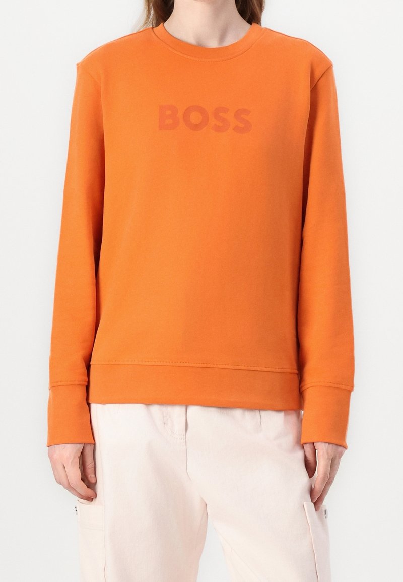 Orange sweatshirt made of cotton, featuring a round neckline and ribbed cuffs. Front displays the text "BOSS" in a slightly darker shade.