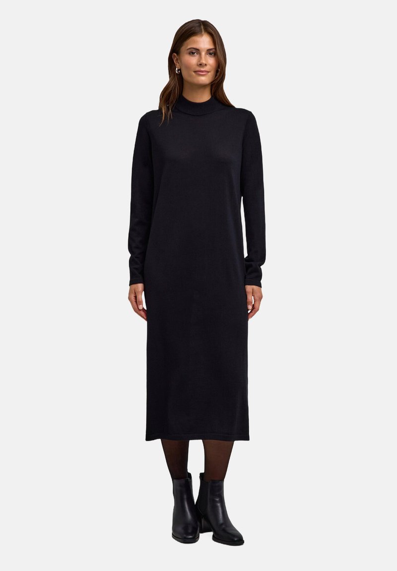 Robe noire à manches longues avec un col haut, fabriquée dans un tissu doux et texturé. La robe est longue jusqu'aux chevilles avec une silhouette droite.