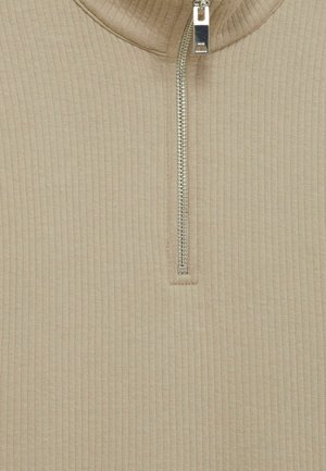 Pullover beige con canalé y cuello con media cremallera. Presenta una cremallera metálica y un patrón de punto texturizado en toda la prenda. Diseño suave y ajustado.