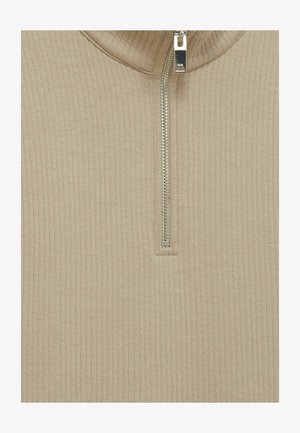 Bežani rebrasti pulover s polu-zip ovratnikom. Sadrži metalni patentni zatvarač i teksturirani pleteni uzorak kroz cijeli komad. Mekan, prilagođen dizajn.