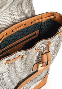 Bolso de tela beige y estampado con un interior verde; cuenta con herrajes dorados, un bolsillo con cremallera y detalles de cuero.