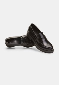 Mustat nahka loaferit, joissa on sileä pinta, ylhäällä risti, pyöreä kärki ja tasainen kumipohja. Yksinkertainen muotoilu korostaa elegancea.