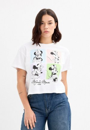 Camiseta corta blanca con un diseño gráfico de Mickey y Minnie Mouse en cuatro paneles, con fondos en tonos pastel y texto debajo.