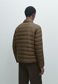 Brun pufferjakke med quiltet design, der har krave, lange ærmer og en afslappet pasform, set bagfra mod en lys baggrund.