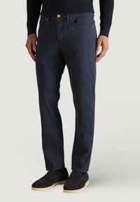 Pantaloni blu navy in cotone, caratterizzati da un design a gamba dritta, cuciture in evidenza e chiusura con bottone dorato, dotati di due tasche frontali.