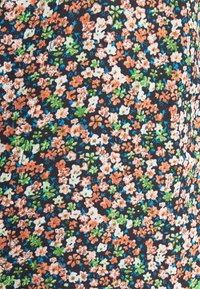 Svart tyg med ett blommönster som har små blommor i orange, vitt, grönt och blått spritt över ytan.