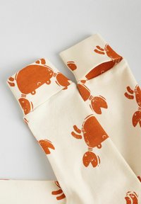 Beige socks featuring a repeating crab pattern in burnt orange, with cuffs showcasing the same design. Made from soft fabric.