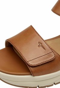 Braune Leder-Sandale mit breitem Riemen, strukturiertem Oberflächenmaterial und einem Klettverschluss. Verfügt über eine gepolsterte Sohle und dezente Logodetails.