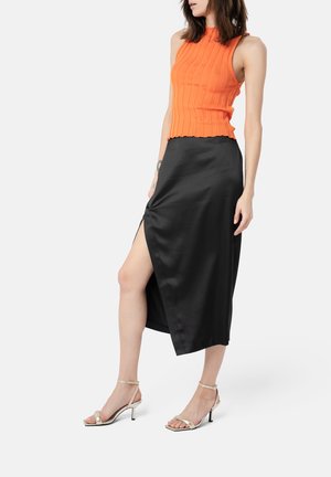 Orange ribbed sleeveless top, black satin midi skirt with side slit, and silver strappy heeled sandals. Smooth texture and fitted design.