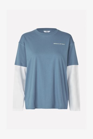 Blå bomuldsblanding langærmet T-shirt med et hvidt lagdelt look, der har teksten "BREAK OF DAY" trykt i hvidt på brystet. Blød tekstur.