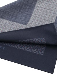 Sciarpa blu navy con texture che presenta un motivo geometrico nei toni grigi e con dettagli rossi, con un bordo piegato che rivela un tessuto a contrasto.