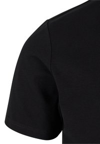 Svart bomulls T-skjorte, korte ermer, rund hals, jevn tekstur, minimal sømdetalj, tettsittende design, sett fra skulder og erme.