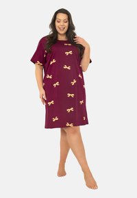 Bordowa koszula nocna z miękkiego materiału, w luźnym kroju, z krótkimi rękawami i żółtymi wzorami w kokardy.