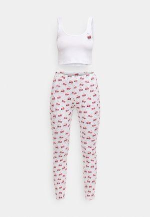 Λευκό crop top με εφαρμογή κερασιού, συνδυασμένο με λευκά κολάν που έχουν επαναλαμβανόμενο μοτίβο κερασιού. Και τα δύο είναι κατασκευασμένα από μαλακό ύφασμα.