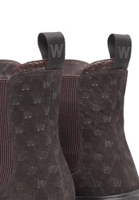 Brown suede ankle boots with elastic side panels, logo texture, and pull-tabs. Features smooth leather accents and a flat rubber sole.