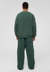Groene sweatshirt en bijpassende wijde broeken met een gestructureerde afwerking, met een achterzak op de broek en ribgebreide manchetten op de sweatshirt.