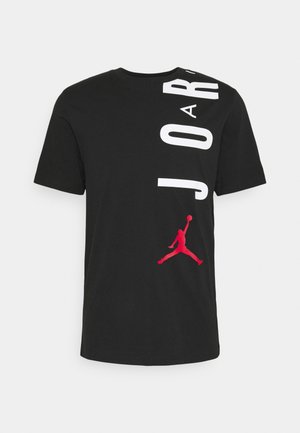 Sort bomulds T-shirt med stor hvid tekst "JORDAN" og et rødt Jumpman-logo på den nederste forside. Kortærmet med rund hals.