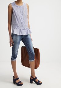 Sleeveless, striped top with a peplum hem, paired with faded jeans. Dark blue platform sandals and a brown tote complete the outfit.