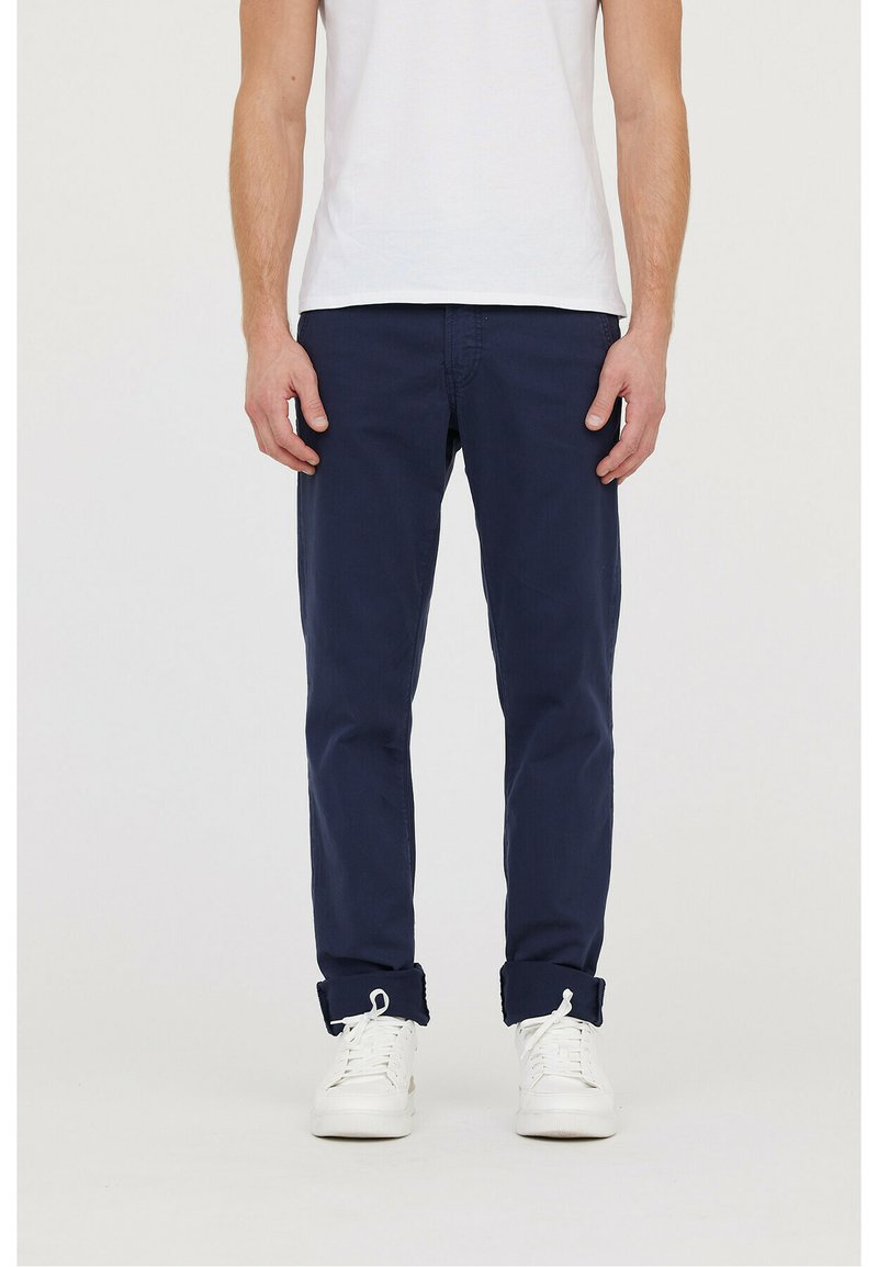 Chinos en coton bleu marine à coupe slim, avec des ourlets roulés et des poches avant, associés à des baskets blanches.