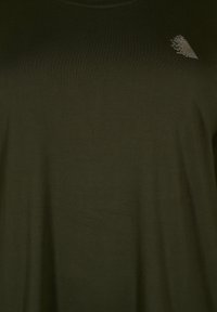 T-shirt verde oliva a maniche corte realizzata in tessuto morbido e leggero, caratterizzata da una sottile trama e un piccolo dettaglio rettangolare sul petto.