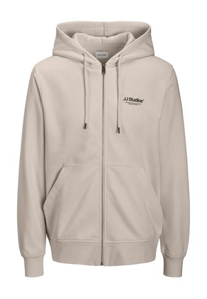 Sudadera con capucha beige claro con cremallera, capucha con cordón, bolsillos delanteros, puños acanalados y logo negro "JJ Studios" en el pecho izquierdo. Tejido suave.