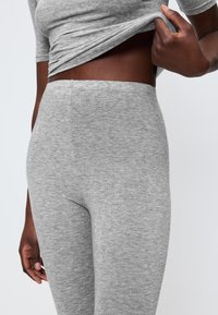 Šedé bavlněné legíny s hladkou strukturou, vysokým pasem a úzkým střihem, spárované s odpovídajícím šedým krátkým rukávem.