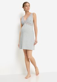 Νυχτικό εγκυμοσύνης από ανοιχτό γκρι βαμβάκι με δαντέλα στο V-λαιμόκοψη και φαρδιές τιράντες, με άνετη εφαρμογή και μήκος μέχρι το γόνατο.