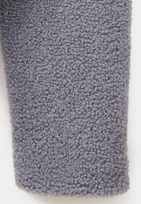 Gros plan d’un tissu polaire doux, gris et bouclé avec une texture dense en boucles.