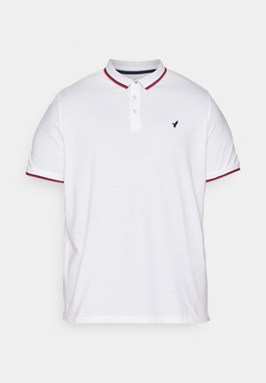 Camiseta polo blanca con cuello, tapeta de tres botones, acentos a rayas rojas y marinas en las mangas, y un pequeño logo negro en el pecho.