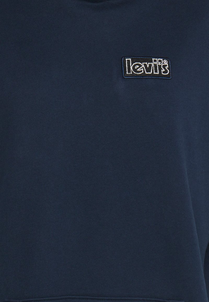 Sweatshirt bleu marine en tissu doux, avec un petit logo Levi's noir brodé en haut à gauche. Texture lisse.