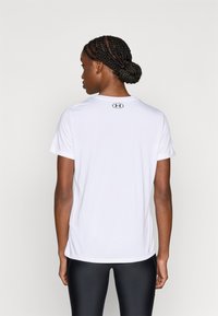 T-shirt de sport blanc à manches courtes avec un col rond, arborant un petit logo noir sur le haut du dos. Tissu lisse et léger.