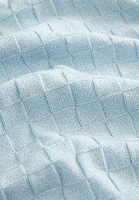 Jasnoniebieska tkanina o fakturowanym wzorze w kratę, wykonana z miękkiej przędzy. Powierzchnia ma gładki wygląd z delikatnie wypukłymi kwadratami.