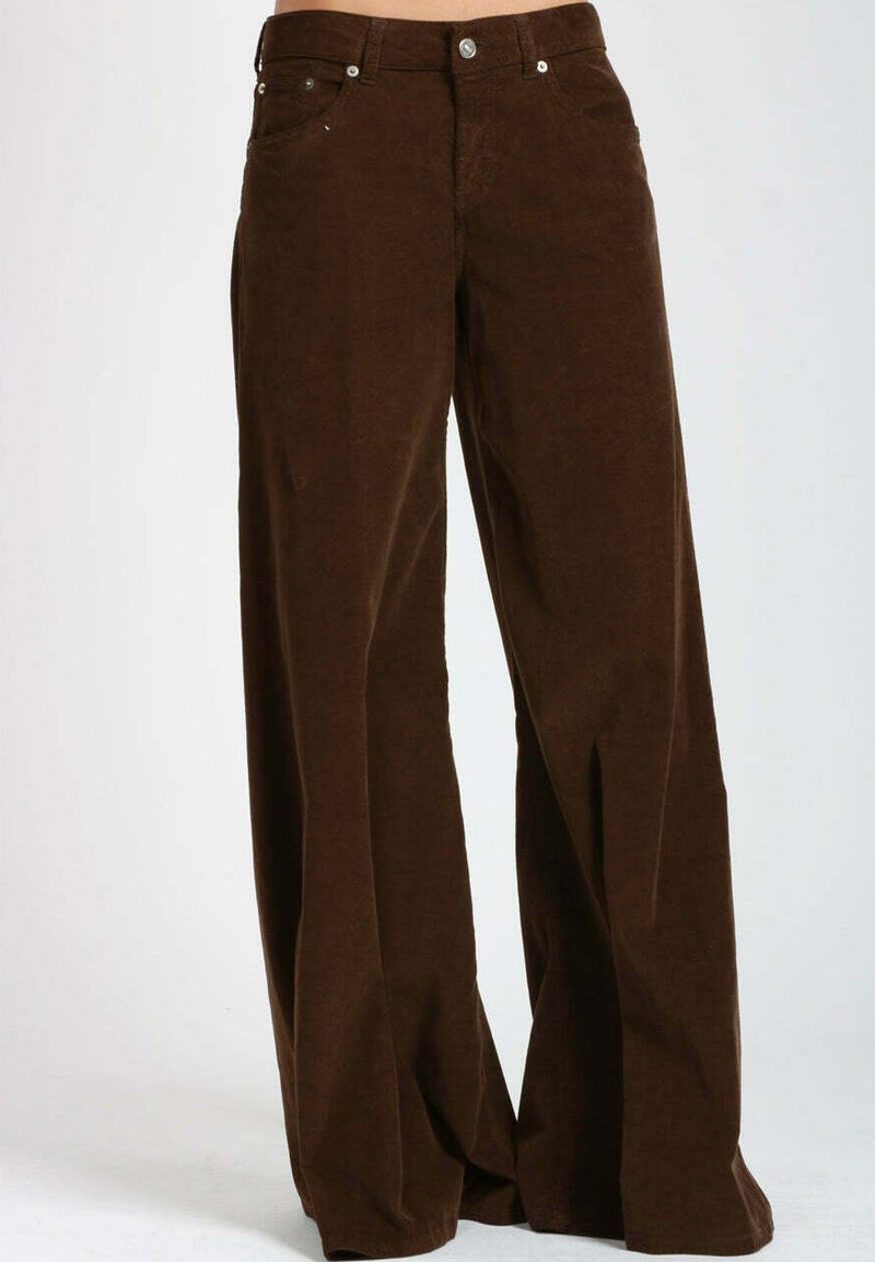 I pantaloni beige in velluto a coste a gamba larga presentano una finitura testurizzata, tasche frontali e dettagli in metallo. Il tessuto mostra una costina verticale.